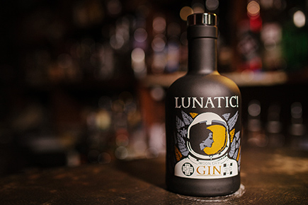Dunkle Flasche des Lunatic Gin auf einer Bartheke