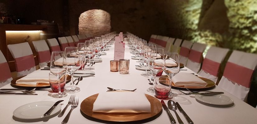 Lange, hell gedeckte Festtafel im Gewölbekeller des Halben Mondes mit goldenen Tellern